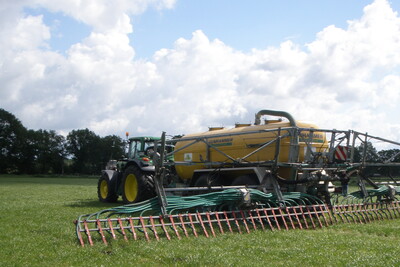 Ausbringung mit Schleppschlauch auf Grünland - © Jelko Djuren Traktor mit großem gelbem Tankanhänger und Verteiler auf einem grünen Feld unter bewölktem Himmel.